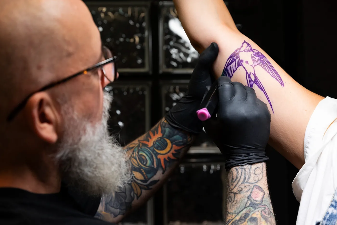 Un tatoueur décalque un motif sur mesure avant de tatouer